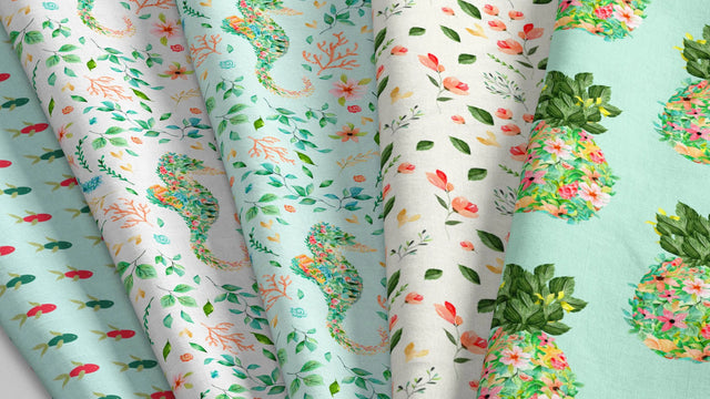 Stack of colorful fabrics with tropical patterns including seahorses, leaves, flowers, and pineapples in shades of green, blue, pink, and white, perfect for quilting beginners choosing materials for their first quilt.
